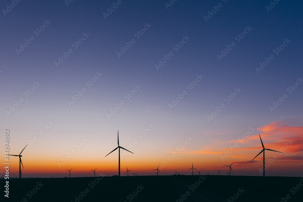 Wind Turbines producing renewable energy at sunset 