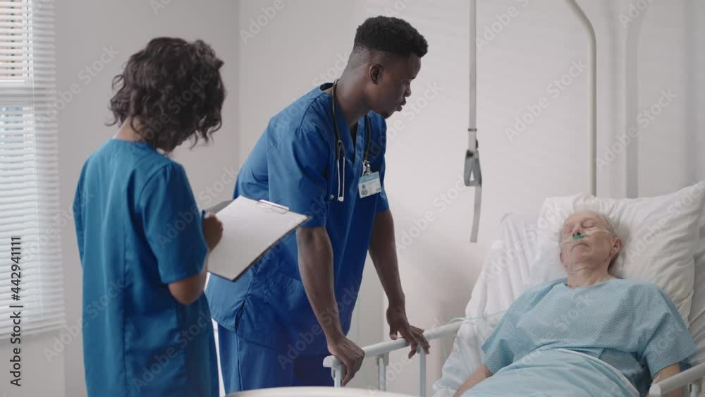 Senior patient on bed talking to 2 African American doctor in hospital room, Health care and insurance concept. Doctor comforting elderly patient in hospital bed or counsel diagnosis health. Senior patient on bed talking to 2 African American doctor in hospital room, Health care and insurance concept. Doctor comforting elderly patient in hospital bed or counsel diagnosis health.