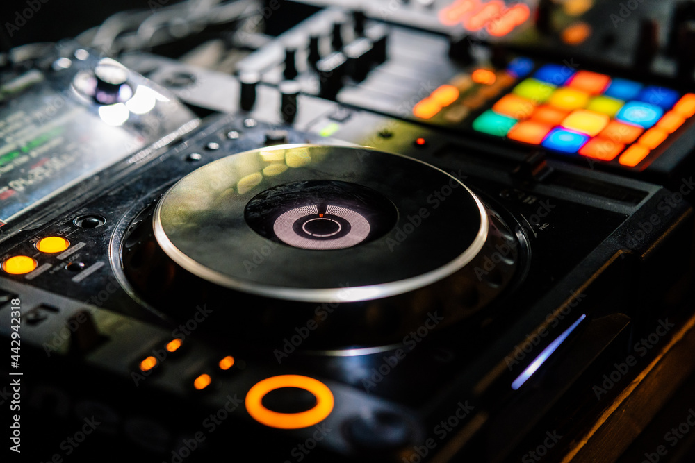 Double track DJ controller with colorful luminous buttons and indicators in nightclub Double track DJ controller with colorful luminous buttons and indicators in nightclub