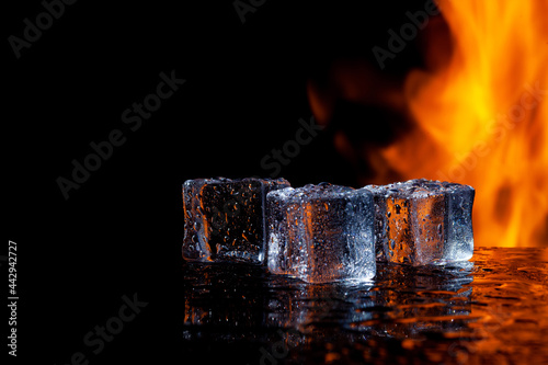 three ice cubes against the background of fire, fire and ice, place under the text