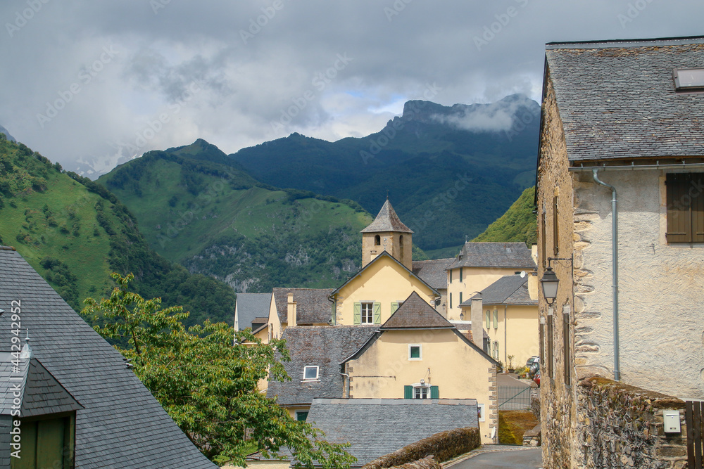 Cette-Eygun, un pequeño pueblo del lado francés de los Pirineos. Paisaje rural de un pequeño pueblo encajado en un valle entre bosques y empinadas montañas. Iglesia de San Pedro al fondo.