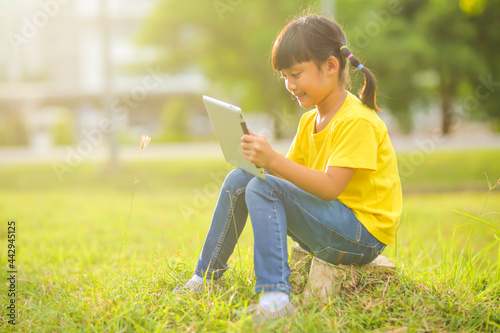 Cute little girl playing with laptop in the park. Which increases the development and enhances outside the classroom learning skills concept.