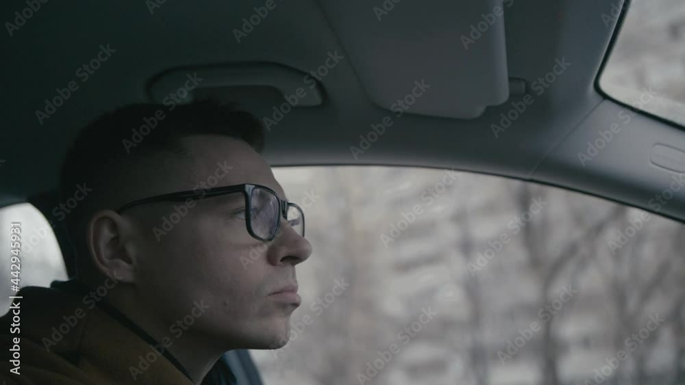 Serious young confident man in coat driving sitting in car. Slow motion. Young businessman driving car in city center. Concentrated driver in moving car. Automobile businessman traffic transportation. Serious young confident man in coat driving sitting in car. Slow motion. Young businessman driving car in city center. Concentrated driver in moving car. Automobile businessman traffic transportation.