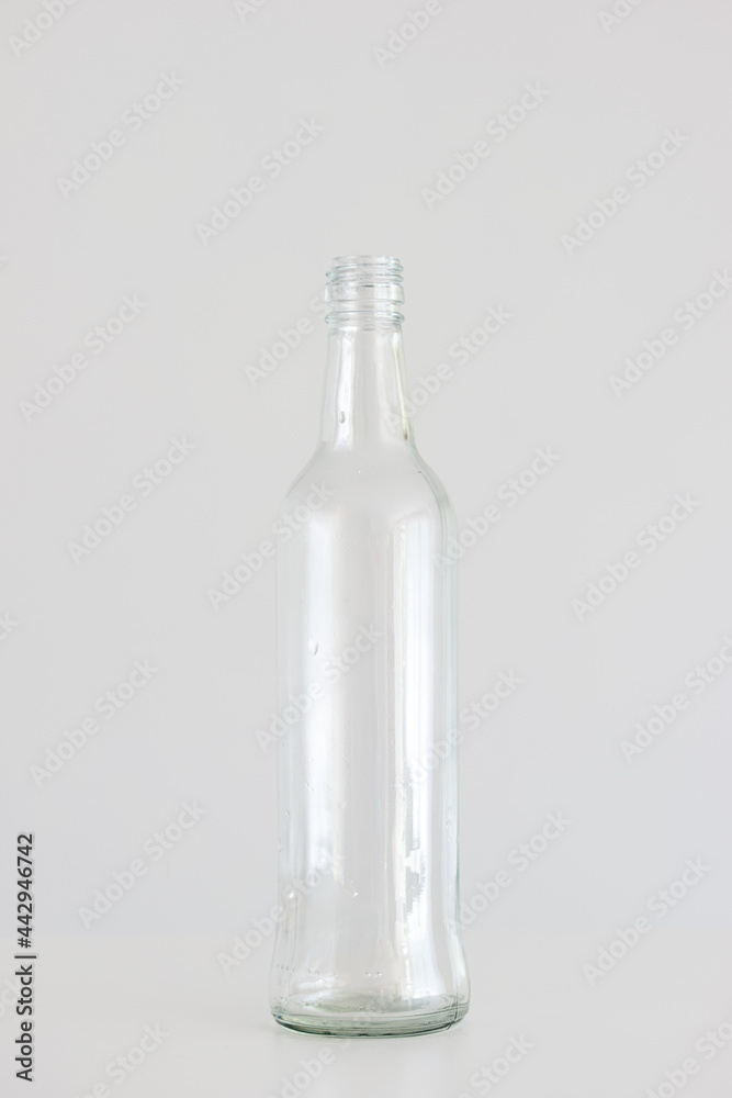 Empty clear glass bottle isolated on light gray background Empty clear glass bottle isolated on light gray background