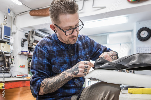 Male artisan sewing upholstery for motorcycle seat