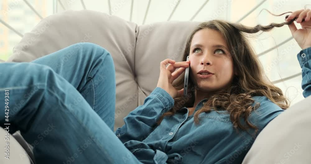 Young woman talking on mobile phone relaxing on luxury chair at home Young woman talking on mobile phone relaxing on luxury chair at home