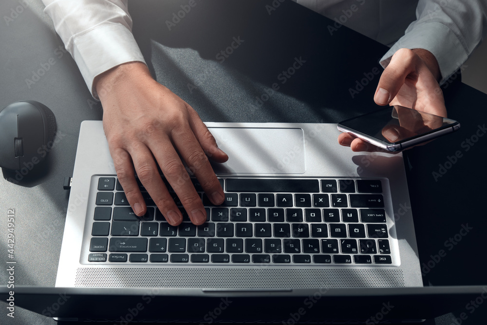 Top view of man hands typing on laptop and smartphone , surfing the internet or online working . business and technology Top view of man hands typing on laptop and smartphone , surfing the internet or online working . business and technology