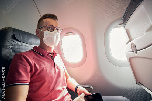 Portrait of passenger with protective face mask in airplane. Themes traveling in new normal and personal protection during pandemic covid-19.