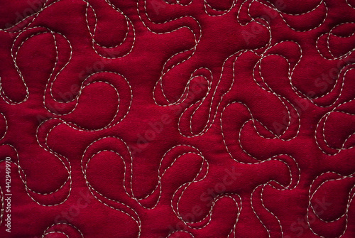 Close up texture of quilting by free-motion machine technique. on dark red clothes Background photo