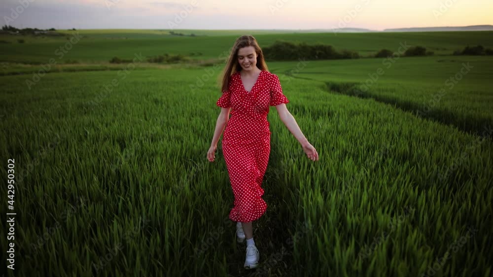 Young beautiful woman in long red dress enjoying freedom and calmness on rural nature in summer. Beautiful carefree woman enjoying nature and sunlight in wheat field at incredible colorful sunset Young beautiful woman in long red dress enjoying freedom and calmness on rural nature in summer. Beautiful carefree woman enjoying nature and sunlight in wheat field at incredible colorful sunset