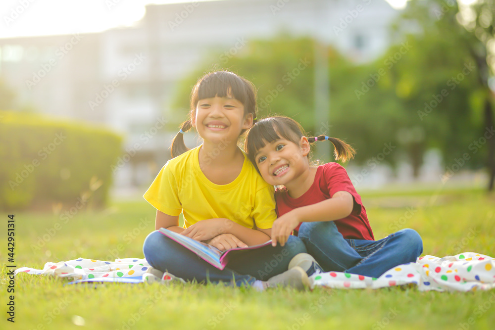 Smiling little asian girl happy small sitting on nature in the park. Which increases the development and enhances outside the classroom learning skills concept. Smiling little asian girl happy small sitting on nature in the park. Which increases the development and enhances outside the classroom learning skills concept.