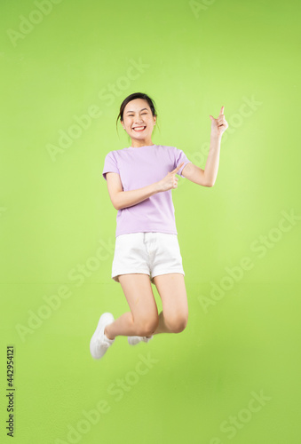 Full body Young Asian girl jumping, isolated on green background