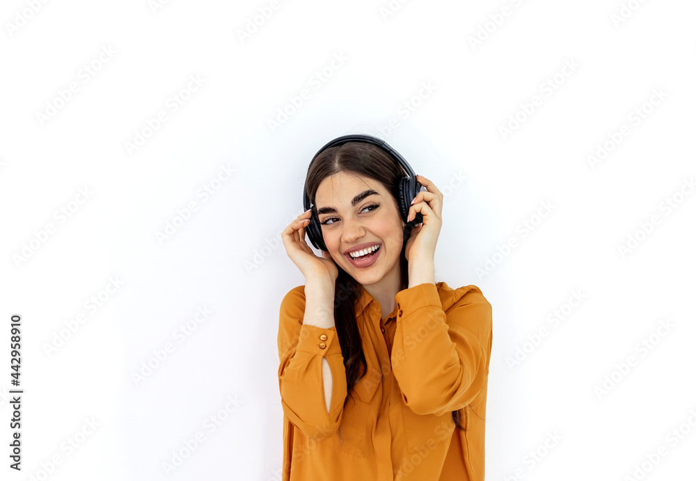 Cropped shot of a beautiful young woman wearing headphones against a grey background. Portrait of smiling young Caucasian woman listening to music with headphones and against isolated white background Cropped shot of a beautiful young woman wearing headphones against a grey background. Portrait of smiling young Caucasian woman listening to music with headphones and against isolated white background