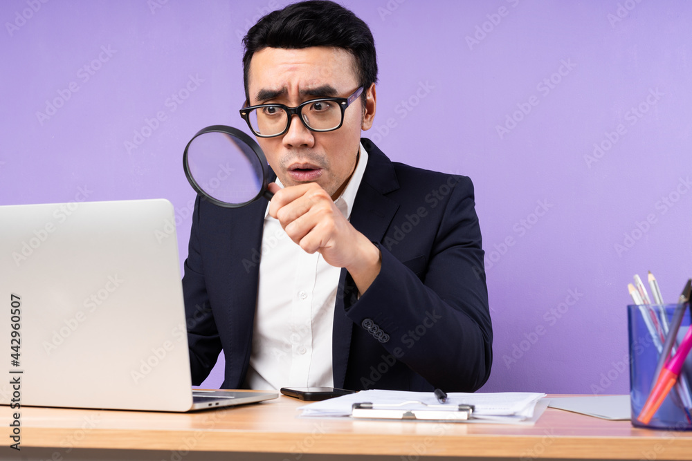 Asian businessman male portrait sitting on desk, isolated on purple background Asian businessman male portrait sitting on desk, isolated on purple background