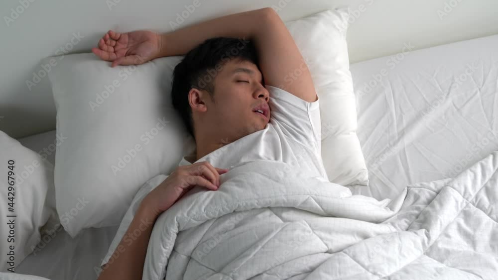 Young Asian man snoring While sleeping in bed.