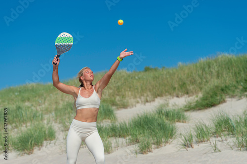 Beach tennis female player serving ball. Professional sport concept