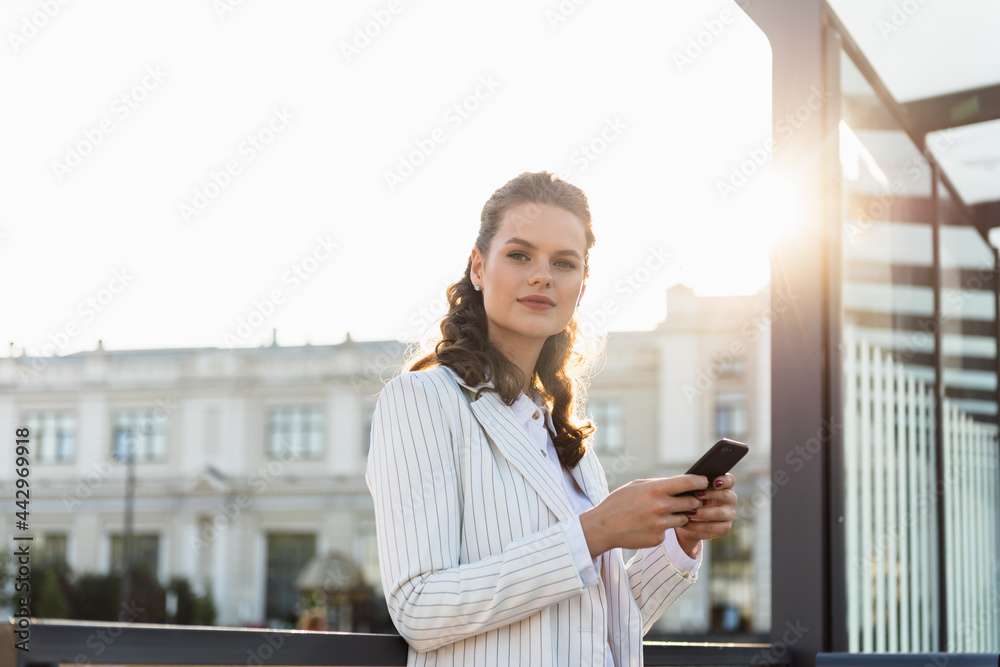 Fototapeta premium An attractive young woman walking in the city center, texting and laughing.