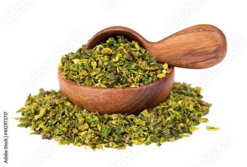 Dried green paprika flakes with seeds in wooden bowl and spoon, isolated on white background. Chopped jalapeno, habanero or chilli pepper. Spices and herbs.