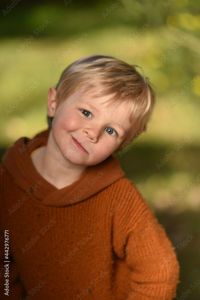 young boy in a park on a background of green foliage