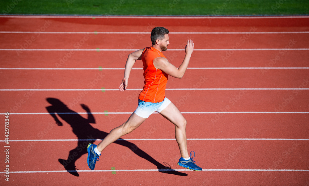 energetic athletic muscular man runner running on racetrack at outdoor stadium, freedom