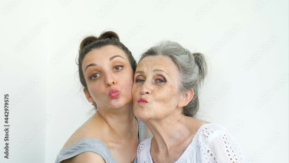 Happy senior mother is hugging her adult daughter, the women are laughing together, sincere family of different age generations having fun on white background Happy senior mother is hugging her adult daughter, the women are laughing together, sincere family of different age generations having fun on white background
