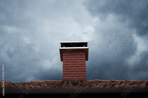 chimney on a roof with storming clouds 