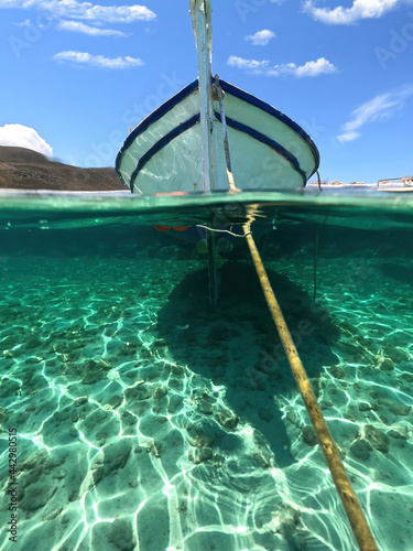 Sea level and underwater split photo of traditional wooden fishing boat anchored in Aegean island port with emerald crystal clear sea