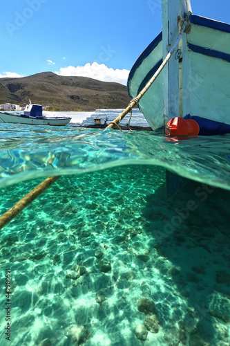 Sea level and underwater split photo of traditional wooden fishing boat anchored in Aegean island port with emerald crystal clear sea