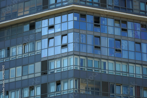  A corner of a modern high-rise glass building with open and closed windows.