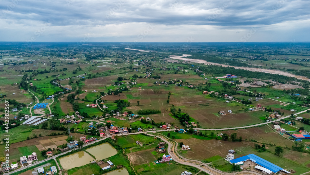 Aerial shot of houses scattered across a large farmland in the countryside Nepal.