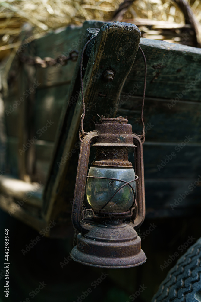 Old rusty kerosene lamp hanging on vintage horse cart in country side