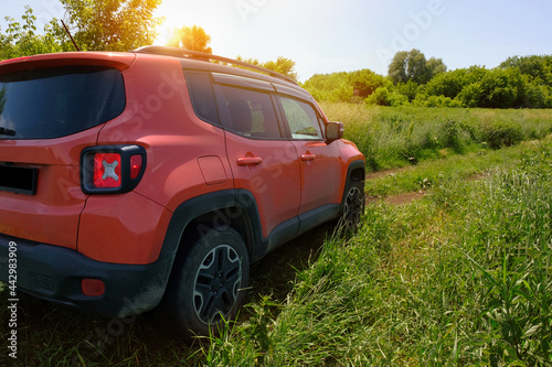 Orange car on a country road in a field, on a sunny day. Travel by off-road vehicle. Transport, travel concept