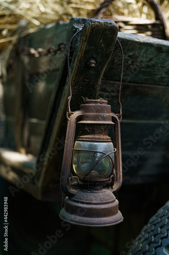 Old rusty kerosene lamp hanging on vintage horse cart in country side © Seweryn