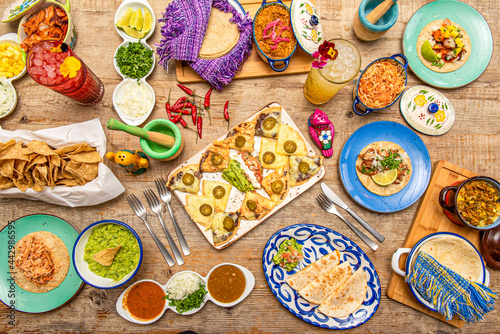 Set of plates and tableware of popular Mexican food. Synchronized quesadillas  Tinga tacos  corn chips  cochinita pibil  tacos al pastor  guacamole in a bowl  enchiladas