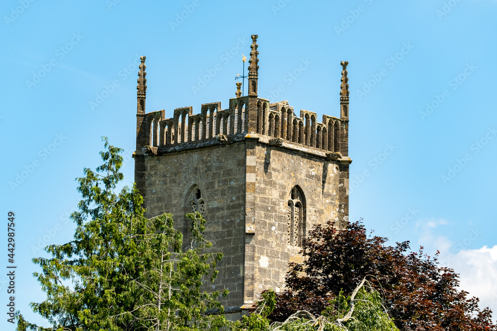 Ancient church spire and trees captured against bright blue sky