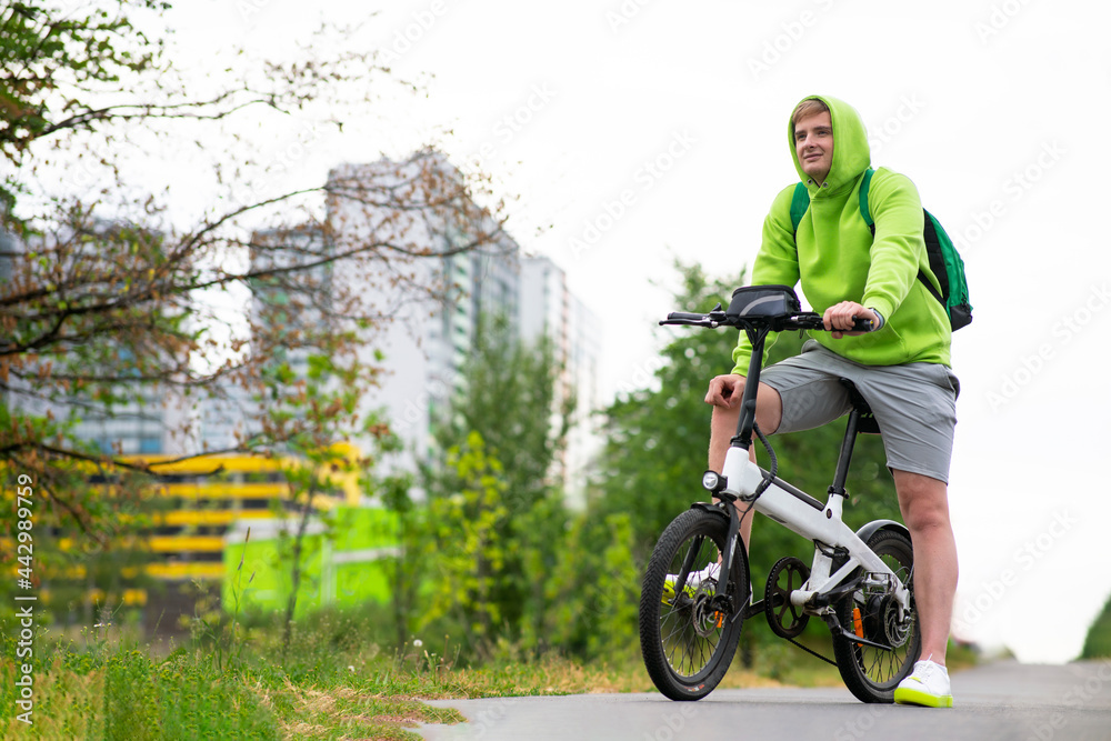 Happy, Young guy riding an electric bicycle, bike in a summer park. Boy Active lifestyle, sports