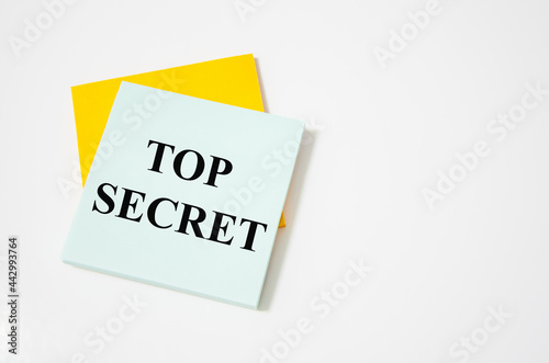 Top Secret text written on a white notepad with colored pencils and a yellow background. word