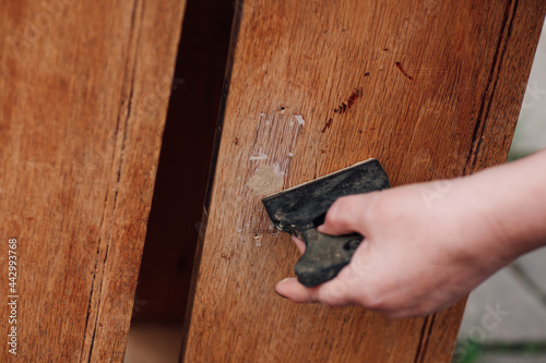 close-up a woman's hand holds a spatula and puts putty on a hole in an old wooden table, recycling workshop.  photo