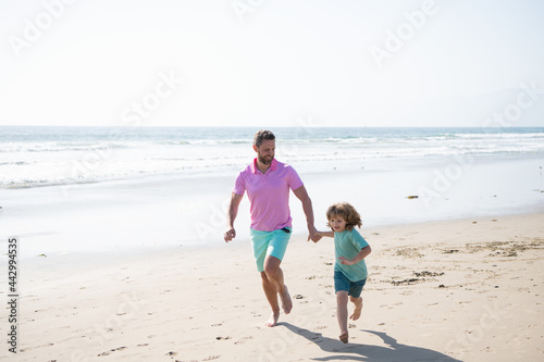 father and son running on summer beach. family travel weekend and vacation.