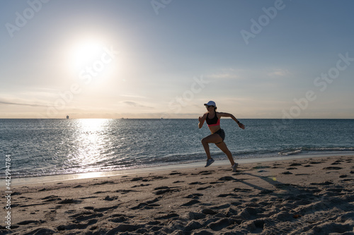 Active woman runner in sportswear run on beach sand along seaside, running