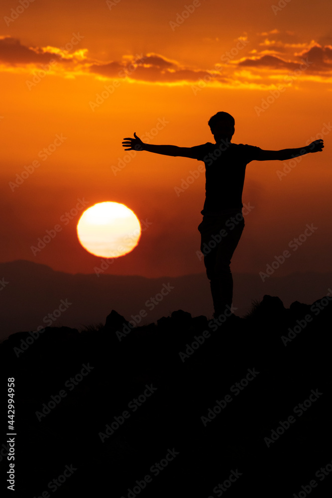silhouette of a man with open armss on the mountain at sunset