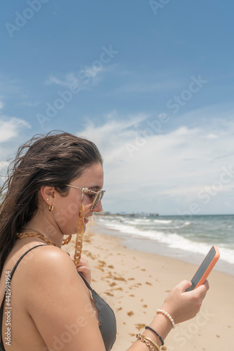 Girl looks at her cell phone on the beach