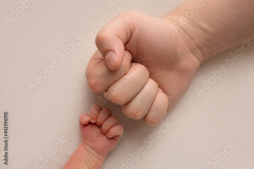 Dad and newborn boy son keep their hands in a fist, small and big fists. Father and son, the first boxing punch.