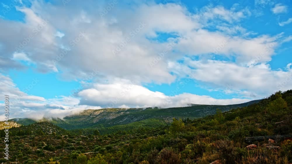 Time-lapse photography of flowing clouds in the blue sky and flowing mist over the mountain in Greece
