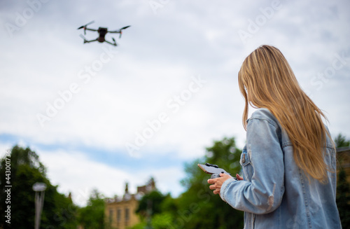 Young beautiful blonde woman piloting a drone holding a remote control
