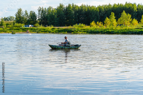 A fisherman in a boat floats on the river.