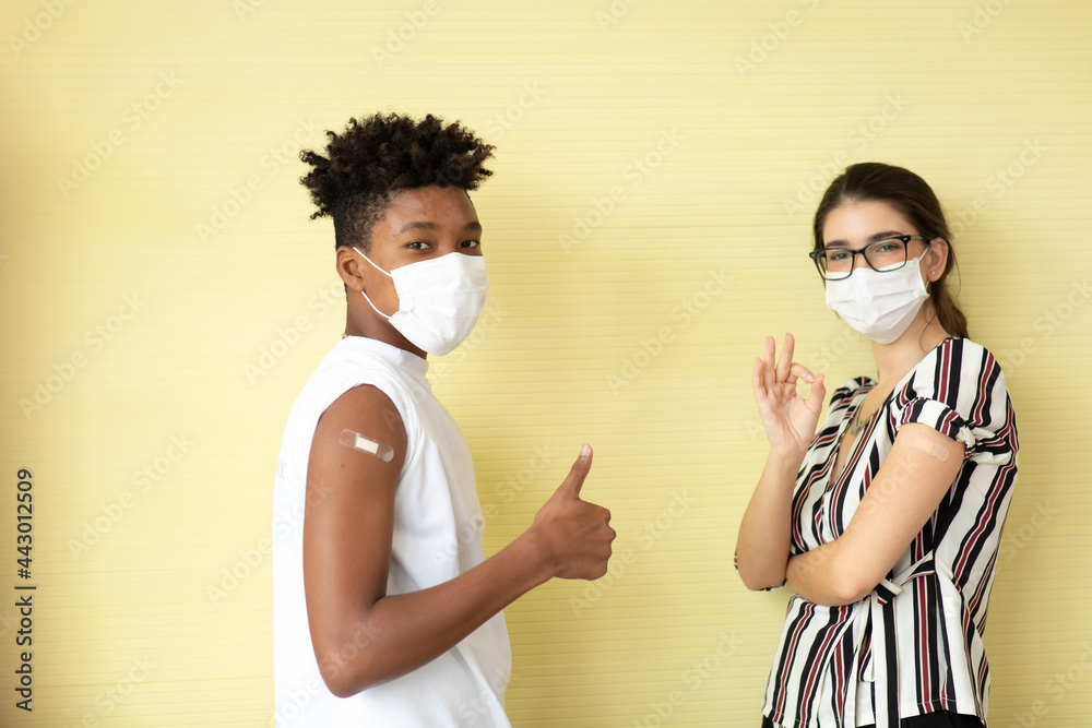 Covid-19 Vaccination concept. portrait  caucasian woman and black young man showing arm with plaster and thumb up or good sign after injection vaccine. New normal greeting each other with their elbows