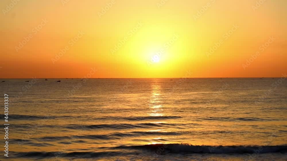 On the rippling sea at sunset, several small boats docked in the distance On the rippling sea at sunset, several small boats docked in the distance