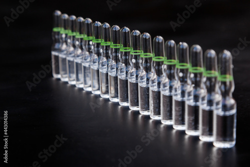 Small glass injection bottles with medicine on a black background.