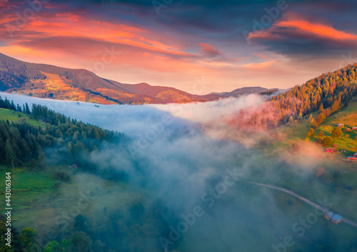 Astonishing autumn sunrise in Carpathian mountains. Fog spreads on the valley of Snidavka village, Ukraine, Europe. Gorgeous landscape of mountain hills glowing by sunlight.